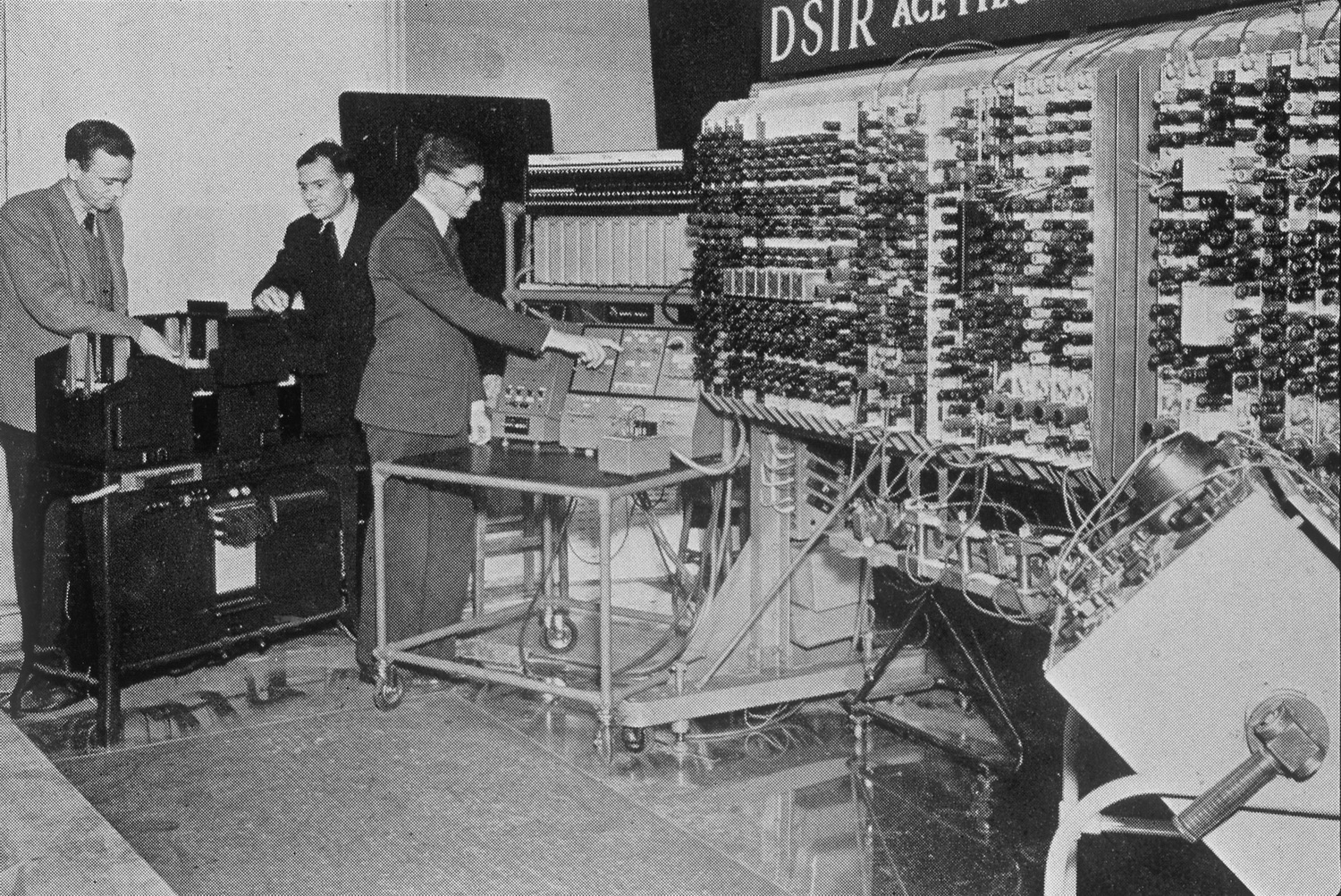 The first public demonstration of the Pilot ACE in 1950. Left to right: Hollerith card punch/reader, operating console, tube rack with short memory tanks.